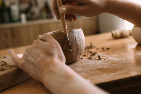 Authors decoration and production of earthenware pottery. Handmade ceramic tableware carving with special tools. hands in clay.の写真素材
