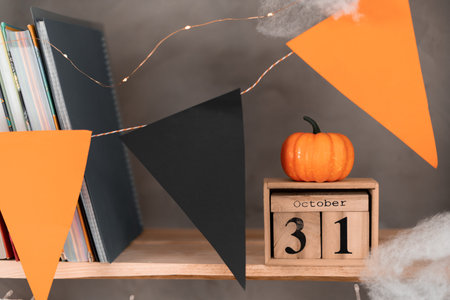 Happy Halloween wooden calendar with the date October 31 on the bookshelf. Pumpkin on the calendar. Flags black orange holiday decorations.の写真素材