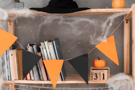 Happy Halloween date October 31 on wooden calendar. bookshelf decoration with orange black flags. Autumn holiday concept.の写真素材