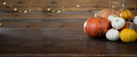 Festive halloween background. Many different pumpkins lie on a wooden table. Autumn harvest of pumpkin seeds. Baner.の写真素材