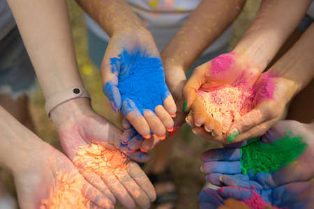 Close-up of human palms with dry paints at Holi Fest festival in city park in summer. Urban holiday. Girlfriends prepare colorful paintsの写真素材