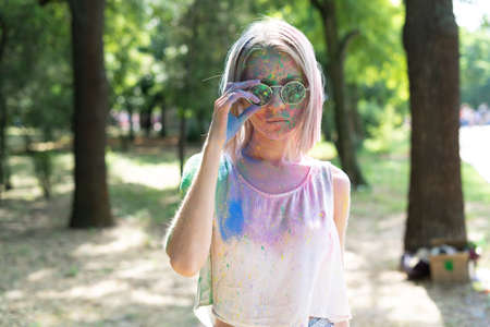 Attractive serious girl in bright colors of Holi. A blonde in powder paints at the Spring Colorfest Festival of Colors. Holi fest celebration concept.の写真素材