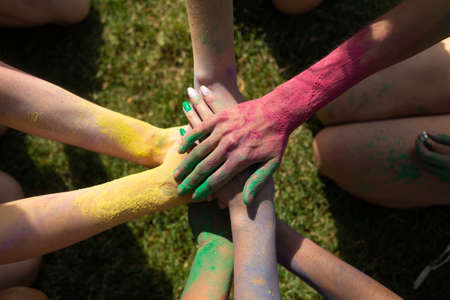 Holi Fest festival womens hands folded as a sign of friendship. Colorfest in the city park. Hand brushes in dry varicoloured paints.の写真素材