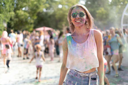 Color Fest and a girl in a white top at the Holi Fest paint festival in a city park hanging in summer on vacation. traditional festival of dry paintsの写真素材