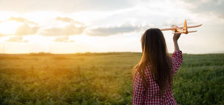 Silhouette of a girl at sunset in a field launching a toy airplane into the sky. Childhood dreams of flying. Walk in the summer in the evening in the field. Children conceptの写真素材