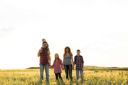 Happy big family mom with dad and children on nature at sunset sky background. Parents and children are walking together. Happy family relationships concept. Childhood and parenting.の写真素材