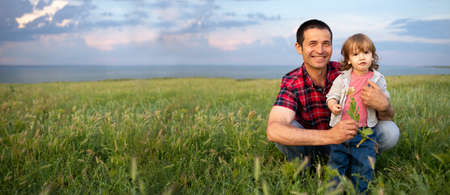 Happy family dad and son on the background of the sunset sky a man sits and holds a child. Fatherhood and childhood outdoor. Family lifestyle concept.の写真素材