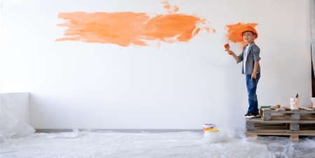 repair of a new house. Child boy painted the wall with paint in the apartment. Children are home designers. Home renovation concept. Banner.の写真素材