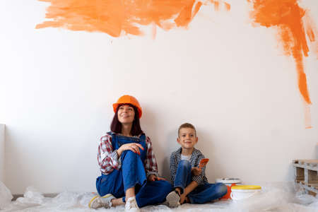 repair of apartments. Mom and son painted the interior wall with designer paint. Orange spots on the wall. Home renovation conceptの写真素材