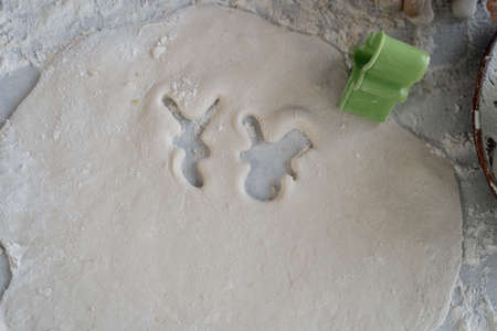 cutting out christmas cookies or gingerbread shape on the table. Sugar cookie mold and raw dough.の写真素材