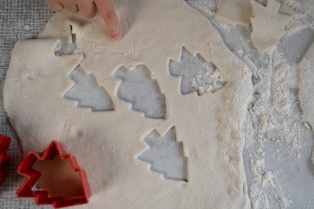 form for Christmas cookies and fresh dough on the table. Cutting gingerbread with a mold with a...