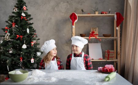 Pretty Caucasian children bakers in the kitchen made flour for Christmas gingerbread cookie dough....