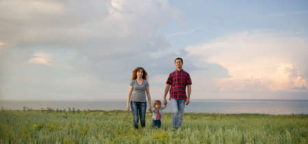 Caucasian family mom dad and little son at sunset. parents and toddler boy on the background of the sky. Freedom. Happy family relationships concept.の写真素材