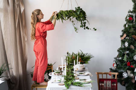 Merry Christmas. A young girl decorates a living room with a large decorated table for the New Year celebration. Interior and decor of the roomの写真素材