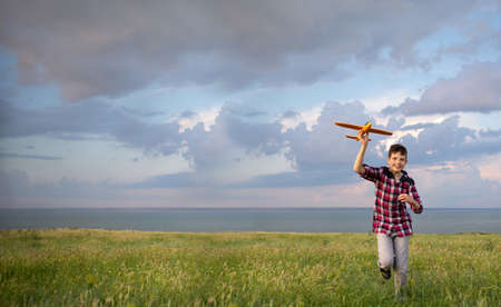 Boy launching an airplane into the sky in autumn at sunset. A teenager dreams of flying an aviator. Active recreation concept in nature.の写真素材