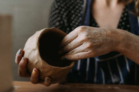 Potter womans hands work with clay. We make a clay bowl by molding. Female hobby conceptの写真素材