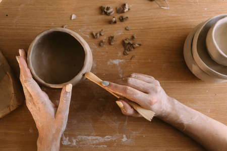 pottery and workshop with clay art concept. close-up on the hands of a young ceramist with an unbaked clay jug. artisan working handsの写真素材