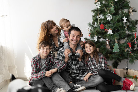 Portrait of a large full Caucasian family with three children at Christmas with gifts sitting on the floor of the house in the living room.の写真素材
