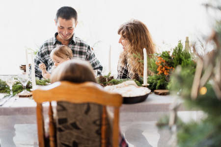 A family with a young son at Christmas dinner. Breakfast for Christmas at a decorated table. Happy family relationships. Christmas homeの写真素材