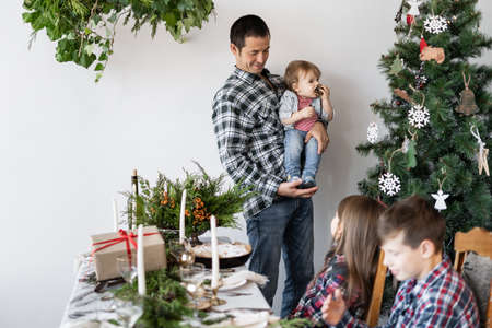 Family, dad with his son near the Christmas tree at home. Family breakfast at Christmas. The father shows his son a fir-tree. Christmas homeの写真素材