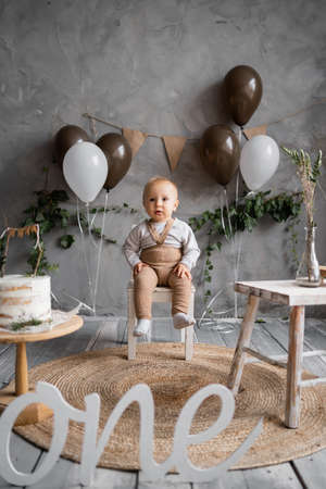 One year old birthday, rustic minimalist decorations and a little boy, balloons and a wooden background, birthday cake. One yearの写真素材