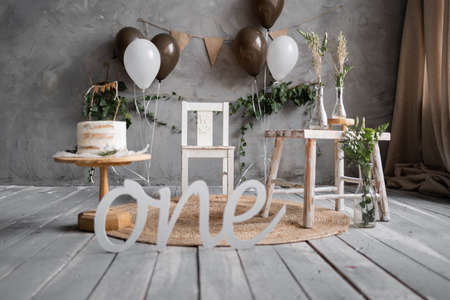 First Birthday photozone, rustic style cake and balloons decorations, wooden floor, gray wall background.の写真素材