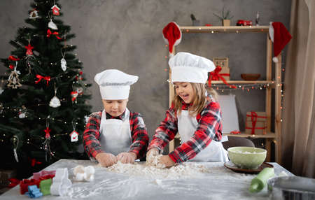Two children kneading dough together, brother and sister making Christmas cookies, baking in the kitchen. Copy space. background.の写真素材