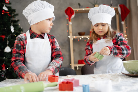 Little brother and sister preparing Christmas cookies in the kitchen, children cutting out dough with a mold, baking in the kitchen. Festiveの写真素材