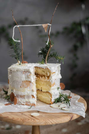 Rustic birthday cake, side cut, white cakes with butter cream, wall background, sponge cake. Decorated wedding cake. Homemade cakes on a tableの写真素材