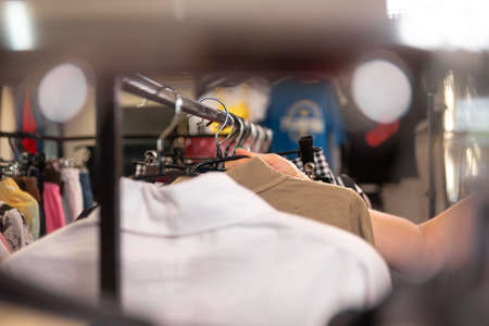 Womans hand choosing clothes hanging on a hanger in a clothing workshop or clothing store, close-up. Backgroundの写真素材