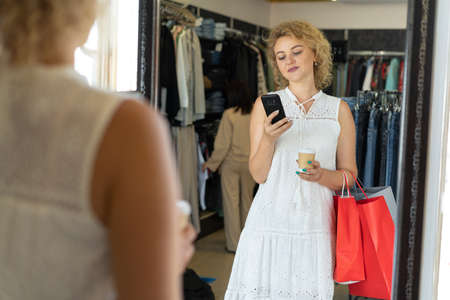 a regular customer of clothes in a store, a female shopping at a sale, a photo in front of a mirror in a fitting room in a boutiqueの写真素材