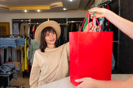 Caucasian woman shopping in clothing store, clothing department and shopper with package at checkout, girl buying on sale, black friday concept.の写真素材