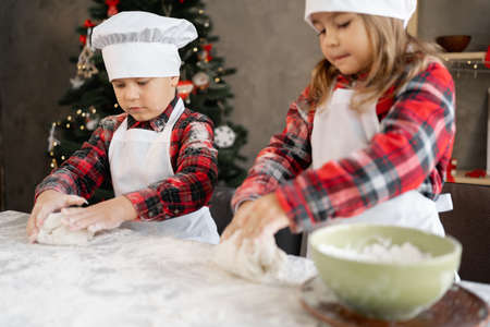 Family, children are preparing Christmas cookies, brother and sister are kneading dough on the table, gingerbread cooking process, preparing foodの写真素材