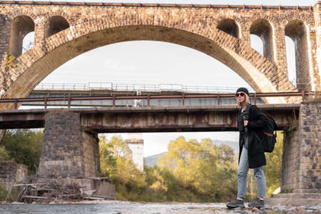 Old arched stone bridge, travel girl tourist near the river, background of the bridge with the railway, urban bridge.の写真素材