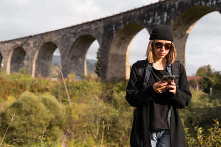 arched stone bridge, europe travel, girl tourist, old bridge background, track search online, female traveler blogger with backpack.の写真素材