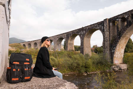 tourist girl resting near the old arch bridge, historical landmark of the railway, stone bridge, architectural structure for trains.の写真素材