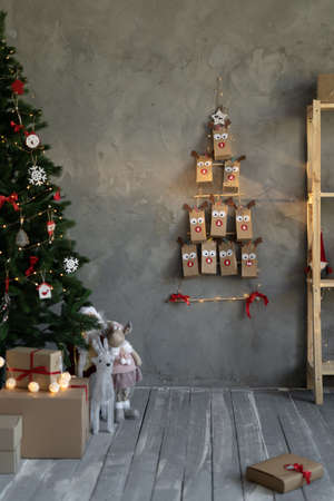 Handmade advent calendar hanging in craft packages on the wall, Christmas decor, living room with Christmas tree, bags with numbers gifts for children.の写真素材