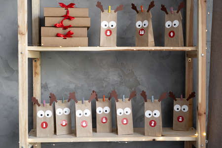 Collection of advent calendar packs wrapped as Christmas gifts in craft paper, standing on a wooden shelf. Decorated with original boxesの写真素材