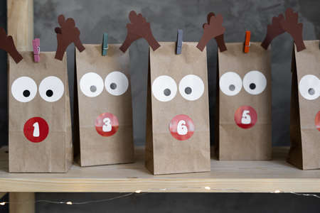Close-up advent calendar in craft packages with numbers of days, Christmas advent presents on the shelf, gray background.の写真素材