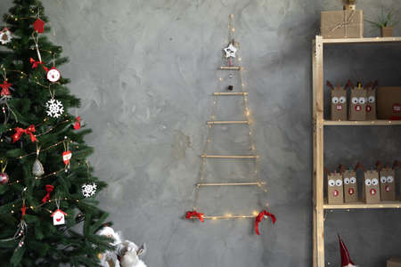 Merry Christmas, living room decorated by Christmas tree and gifts in packages on the shelf. Advent calendar for the holiday, gray wall background.の写真素材