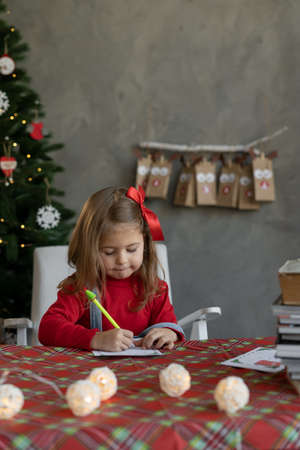 Caucasian little girl writes a Christmas letter to Santa, the child makes a list of gifts for the New Year, Happy festive childhood.の写真素材