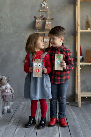 Happy kids with craft packs of Christmas advent calendar, brother and sister joy from pack with number 1, Christmas kids fanの写真素材