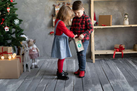 Children brother and sister with gift packages advent calendar number 1, handmade calendar in craft packaging, diy gifts for toddlers.の写真素材