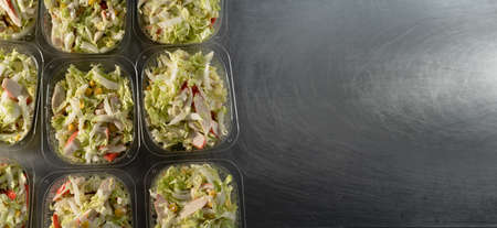 food in disposable dishes on a black background, vegetable salad in plastic containers, ordering lunch in a restaurant, food delivery conceptの写真素材