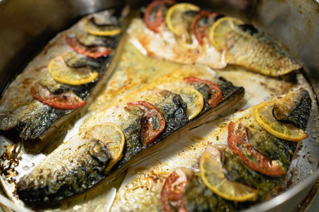 grilled mackerel fish under lemon with herbs and tomato, sea fish in a restaurant for dinner, appetizing fish fillet, dark food background, sea menuの写真素材