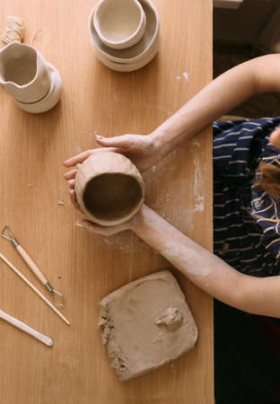 The hands of a woman potter work with clay. We make a clay bowl with molding. Female hobby conceptの写真素材