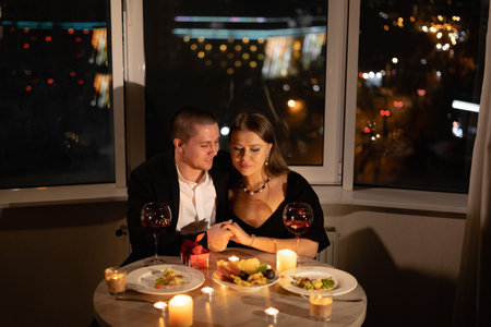 romantic dinner for two with candles, date by candlelight with wine, couple in love on valentines day, man and woman relationship holiday at homeの写真素材