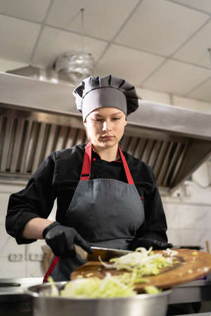 takeaway food in the restaurant. woman chef in special clothes in the kitchen prepares cabbage salad. Food delivery.の写真素材
