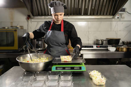 Food delivery, chef cooking charity lunch in plastic containers, small business takeaway food, weigh food on scales in restaurant, lunch delivery serviceの写真素材
