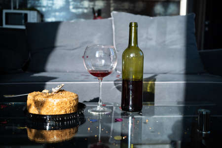 birthday at home, cake and glass of red wine, alcohol for valentine's day, bottle of wine on the table next to dessert, valentine's day celebration conceptの写真素材